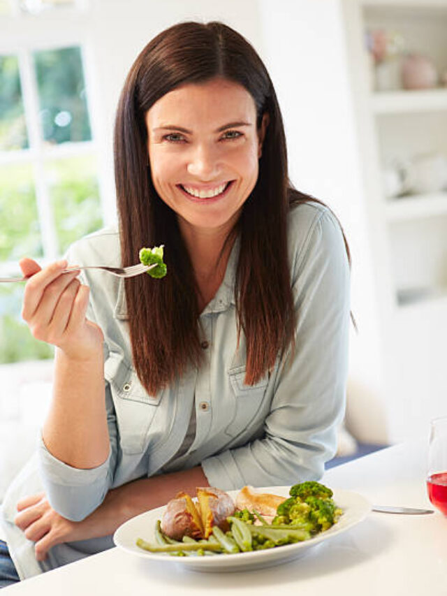 Portrait Of Woman Eating Healthy Meal In Kitchen Smiling To Camera