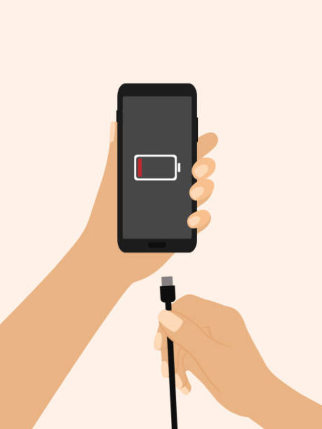 Hand Holding A Mobile Phone And Charger. Low Battery Symbol On Phone Screen