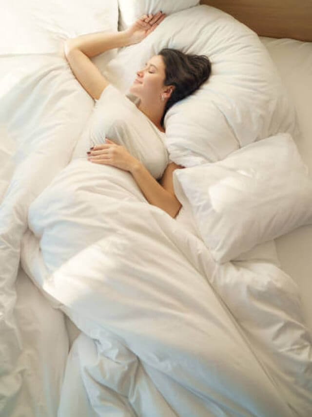 Young woman waking up and streching on bed in the morning